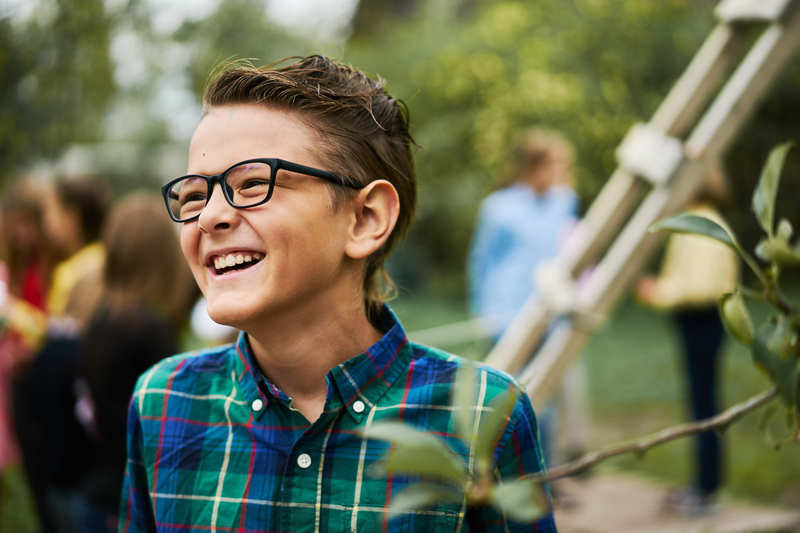A boy in glasses and a plaid shirt at an outdoor event
