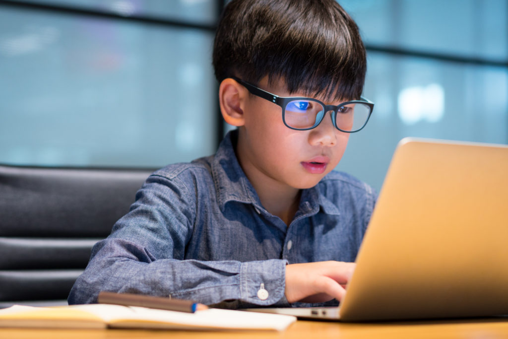 A child in specs working on laptop